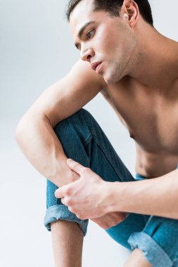 düşünceli ve gömleksiz adam beyaz üzerinde mavi kot oturan 