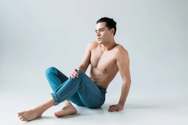 Bonito Homem Posando Enquanto Sentado Azul Jeans Branco — Fotografia de Stock