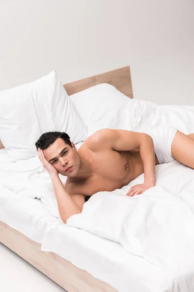심각한 근육과 셔츠없는 남자는 카메라를보고 침대에 — 스톡 사진