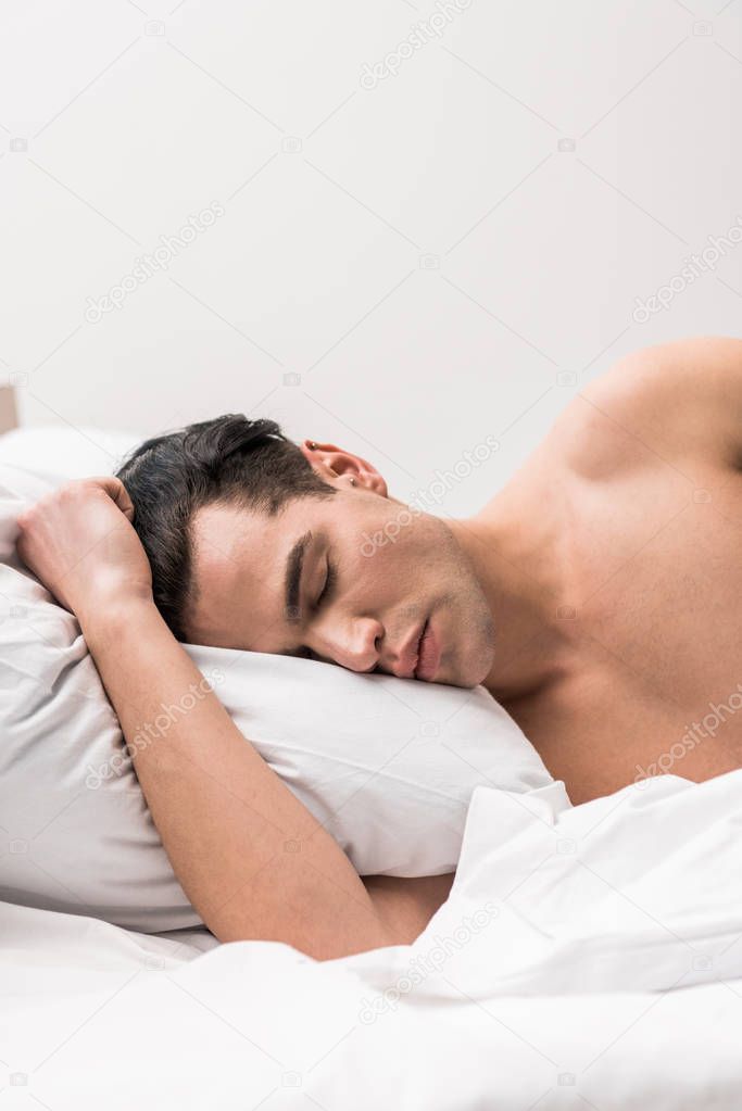handsome and shirtless man lying on bed with closed eyes