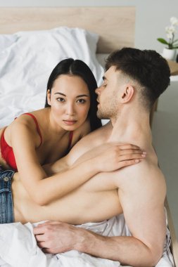 seksi asyalı kadın gömleksiz yakışıklı erkek arkadaşı kucaklayan kamera bakıyor