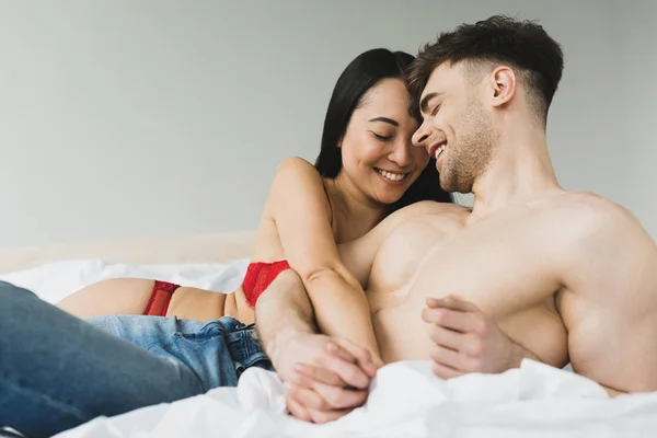 Vrolijke Interraciale Paar Glimlachend Vasthouden Van Handen Terwijl Liggend Bed — Stockfoto