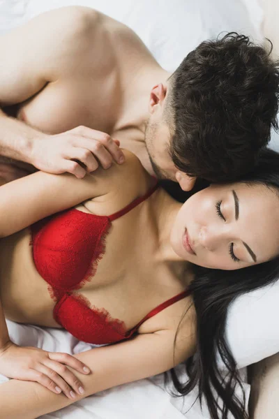 Young Shirtless Man Embracing Sexy Asian Girlfriend Lying Bed Red — Zdjęcie stockowe