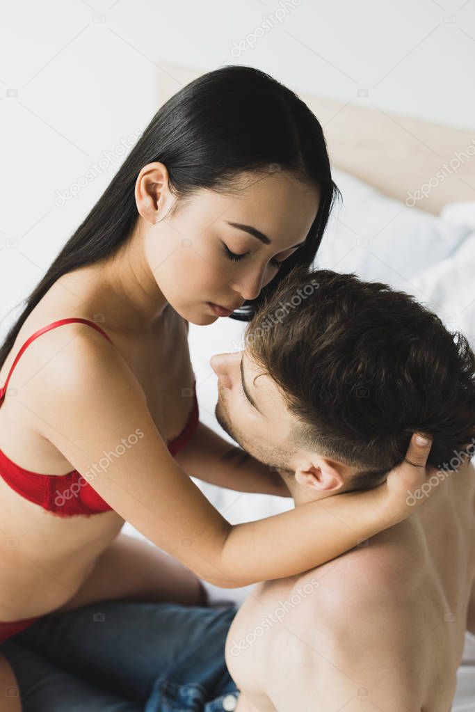 overhead view of loving interracial couple embracing in bedroom