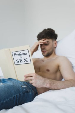 ciddi gömleksiz adam mavi kot yatakta yatarken seks kitabında sorunları okuma