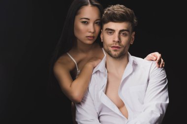 güzel asyalı kadın yakışıklı erkek arkadaşı sarılma ve siyah izole kamera bakıyor