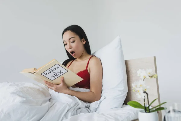 Chocado Ásia Mulher Leitura Problemas Sexo Livro Enquanto Deitado Cama — Fotografia de Stock