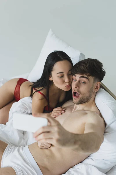 Selektywny Fokus Sexy Asian Kobieta Całowanie Wesoły Chłopak Biorąc Selfie — Zdjęcie stockowe