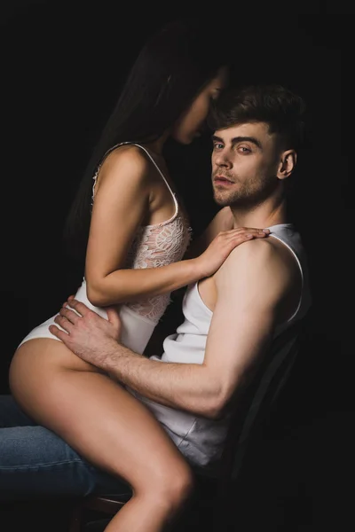 性感的女人在白色内衣坐在膝盖的英俊男子孤立在黑色 — 图库照片
