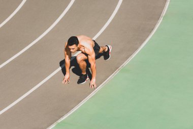 mixed race sportsman preparing to run at stadium clipart