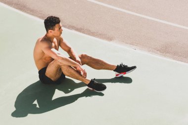 stadyumda oturan yorgun yakışıklı karışık yarış sporcusu