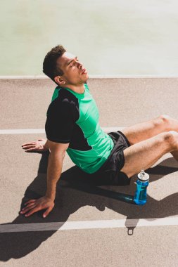 stadyumda oturan yorgun yakışıklı karışık yarış sporcusu