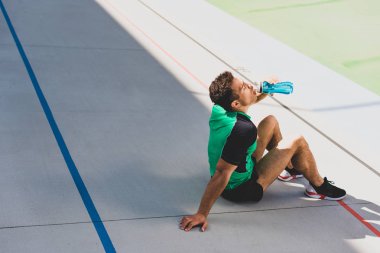 mavi şişeden pistte çalışan ve İçme suyunda oturan karışık yarış sporcusu 