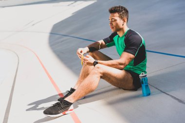 Karma yarış sporcusu mavi şişe ve açılış çikolata yakınında koşu pistinde oturan
