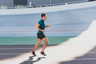 Stadyum pistinde çalışan karma yarış sporcunun yan görünümü