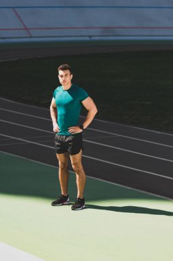 stadyumda kalça elleri ile karışık yarış sporcusu ayakta ve kamera bakıyor