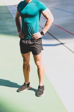 güneş ışığında stadyumda kalça elleri ile sporcunun ayakta görünümü kırpılmış