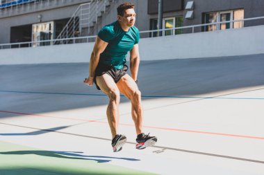 karışık yarış sporcusu güneş ışığında stadyumda uzun atlama yapıyor