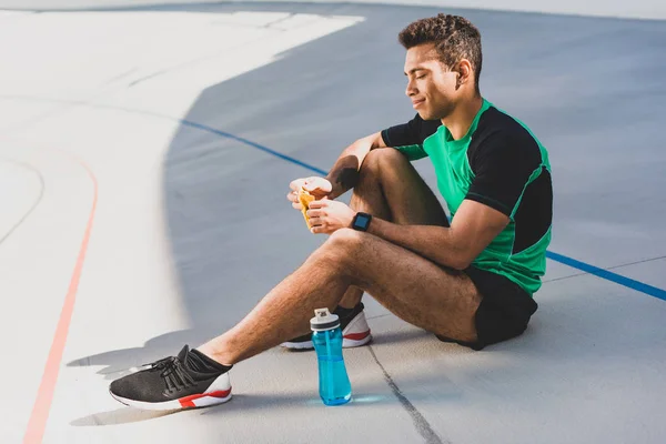 Side View Mixed Race Sportsman Sitting Running Track Blue Bottle — Stock Photo, Image