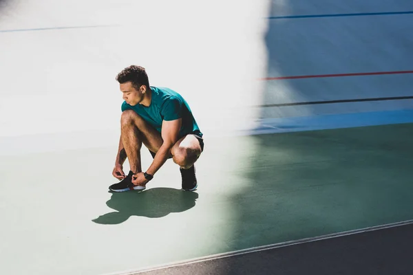 Mestiço Desportista Amarrando Tênis Estádio Chão Verde — Fotografia de Stock