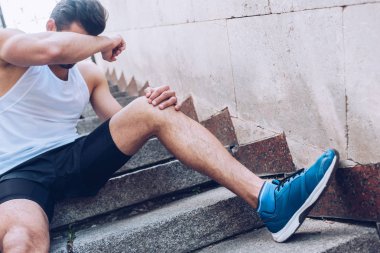merdivenlerde otururken ve el ile yüz kaplama sırasında ağrı muzdarip üzgün yaralı sporcu