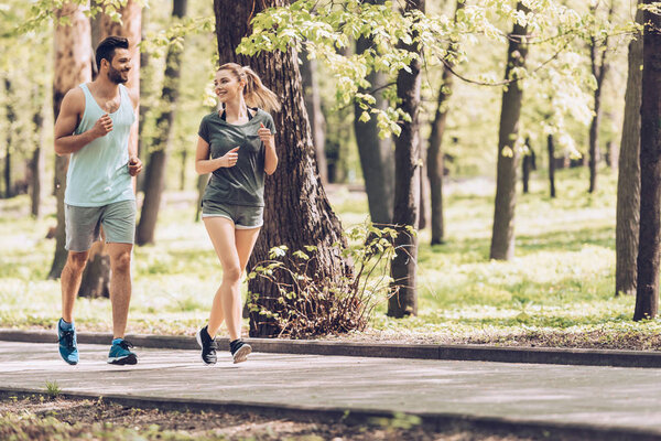 Красивый мужчина и привлекательная женщина разговаривают во время пробежки в парке
