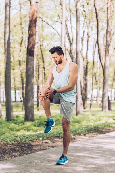 Handsome Sportsman Touching Injured Knee While Standing Park — Stock Photo, Image