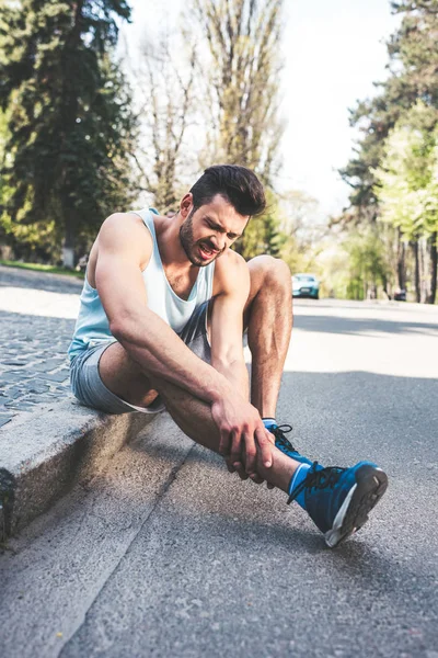 Schöner Sportler Der Verletztes Bein Berührt Während Der Grenze Sitzt — Stockfoto