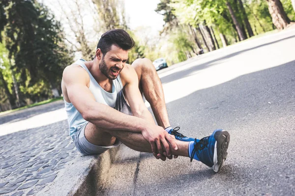 Injured Sportsman Suffering Pain While Sitting Pavement Border Touching Leg — Stock Photo, Image