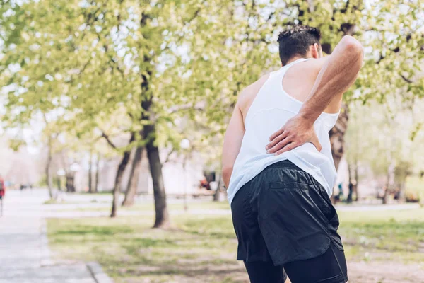 부상을 허리를 만지면서 통증을 앓고있는 스포츠맨의 뒷모습 — 스톡 사진