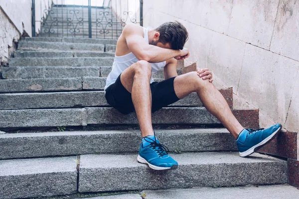 階段に座っている間に痛みに苦しむ負傷したスポーツマン — ストック写真