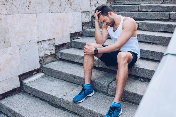 계단에 앉아서 근처에 잡고있는 고통을 스포츠맨 — 스톡 사진