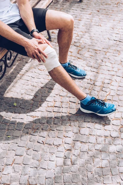 Partial View Sportsman Sneakers Sitting Bench Touching Elastic Bandage Injured — Stock Photo, Image