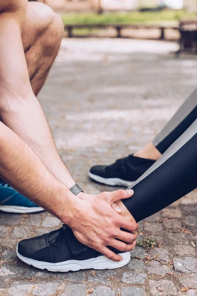 운동화에 스포츠 우먼의 다리를 만지는 스포츠맨의 부분보기 — 스톡 사진