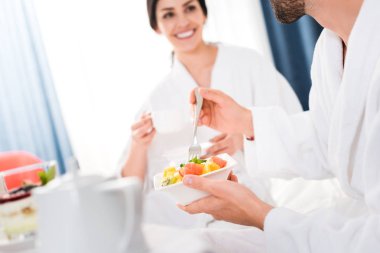 mutlu kadın yakın meyve salatası ile çatal ve kase tutan adam kırpılmış görünümü 