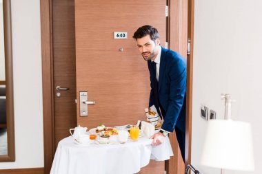 otel yemek arabası üzerinde kahvaltı getiren resmi giyim mutlu adam seçici odak 