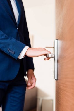 cropped view of man standing near door and touching door handle  clipart