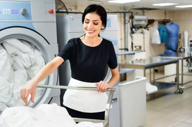 beyaz çarşaf ile sepet yakınında gülümseyen hizmetçi seçici odak