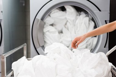 cropped view of housemaid near white bed sheets in laundry  clipart