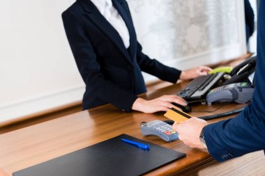 otelde kredi kartı tutarken adam ödeme kırpılmış görünümü 