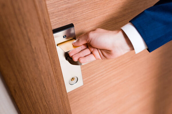 cropped view of man using hotel card while opening door 