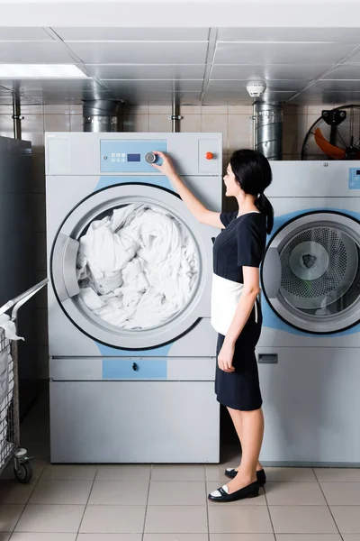 Brünettes Dienstmädchen Steht Und Knopf Waschmaschine Wäscherei Berührt — Stockfoto