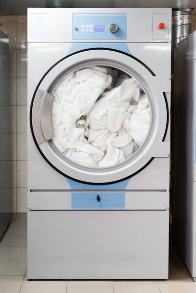 белые простыни в электрической стиральной машине в прачечной в отеле
 