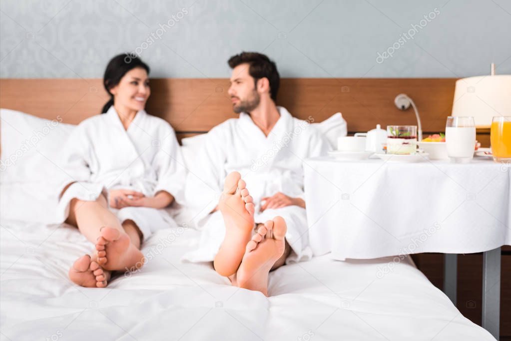 selective focus of happy man and woman looking at each other near table with breakfast 
