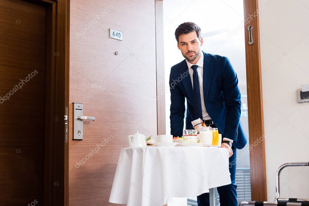 selective focus of handsome receptionist bringing breakfast on food trolley 