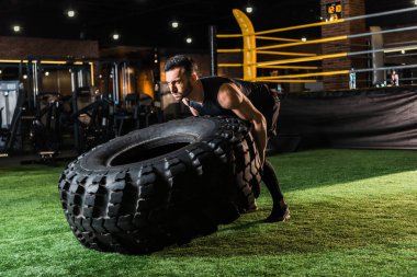 güçlü atletik adam yeşil çim üzerinde büyük araba lastiği ile çalışma 