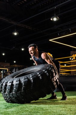 yeşil çim üzerinde büyük araba lastiği ile çalışan atletik sakallı adam düşük açı görünümü 