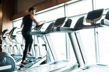 spor salonunda egzersiz bisikleti üzerinde çalışan atletik ve yakışıklı adam düşük açı görünümü 