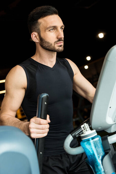 selective focus of athletic man working out on exercise bike 