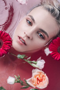 renkli pembe su ve çiçeklerile küvette yatan güzel genç kadın üst görünümü